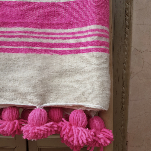 white pompom blanket with pink stripes